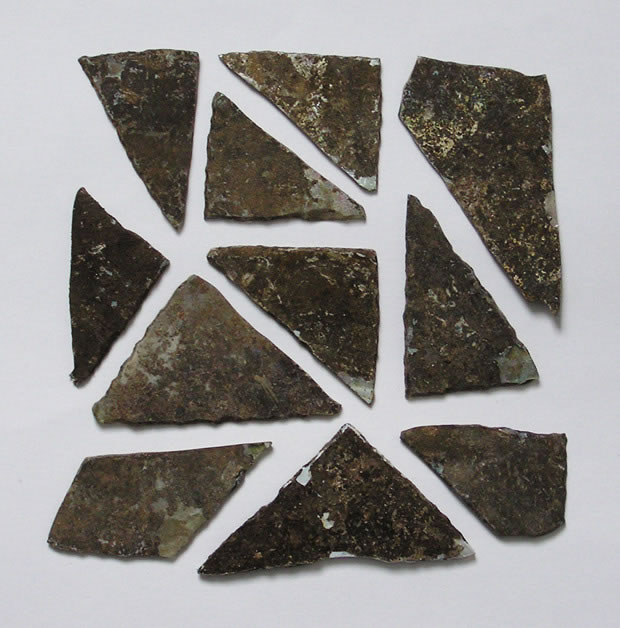 Photographie : Quelques fragments de vitraux taillés en triangle (crédit L. Pirault / INRAP, 2005)